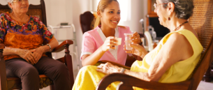 caregiver giving a medicine while two senior women are talking