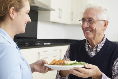 caregiver serving breakfast to senior man