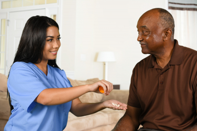 caregiver serving a medical pill to senior man